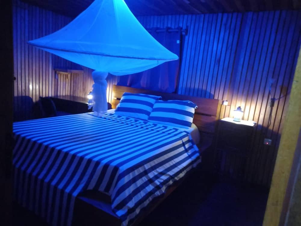 een slaapkamer met een bed met een blauw licht erop bij Appartement Chalet type f3 in Kribi