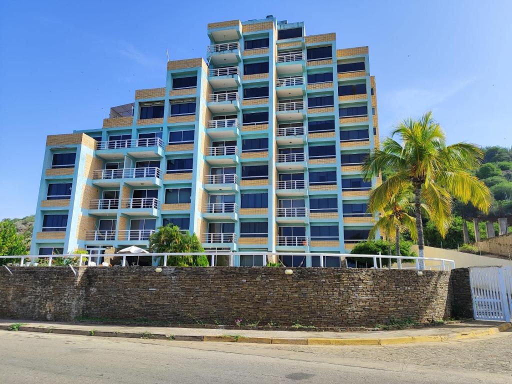 un edificio alto con palmeras delante en Playa dorada en Pampatar