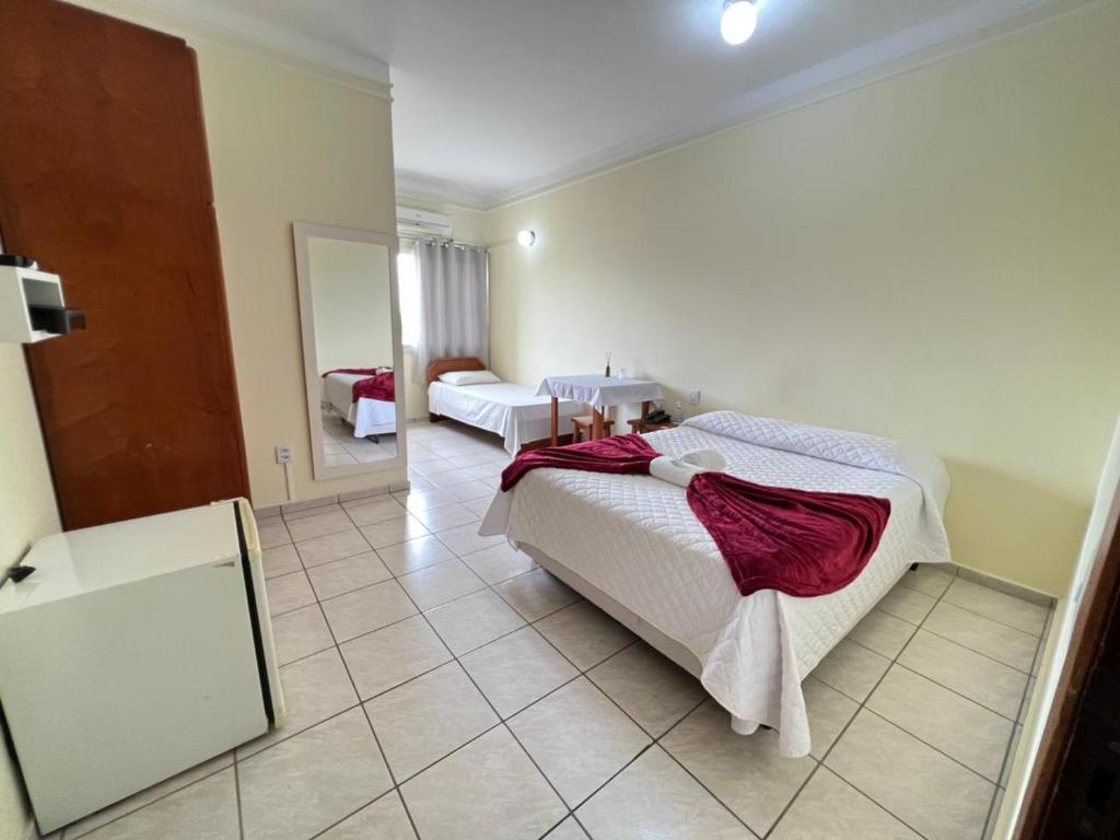 1 dormitorio con 1 cama grande y espejo en Capão Praia Hotel, en Capão da Canoa