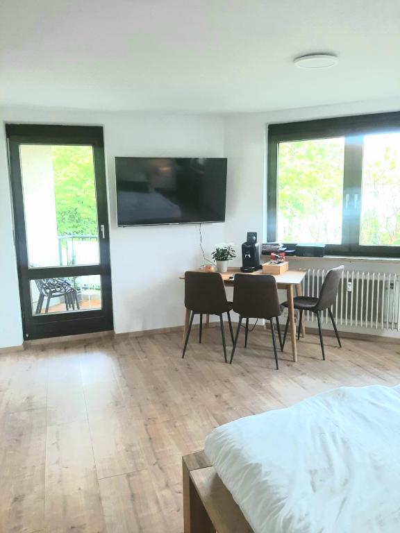 1 dormitorio con mesa, sillas y TV en la pared en Helle freundliche Wohnung am Stadtpark, en Bobingen