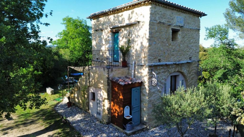 une ancienne maison en pierre avec un balcon et des arbres dans l'établissement Le Pigeonnier du Château, à Saint-Victor-de-Malcap