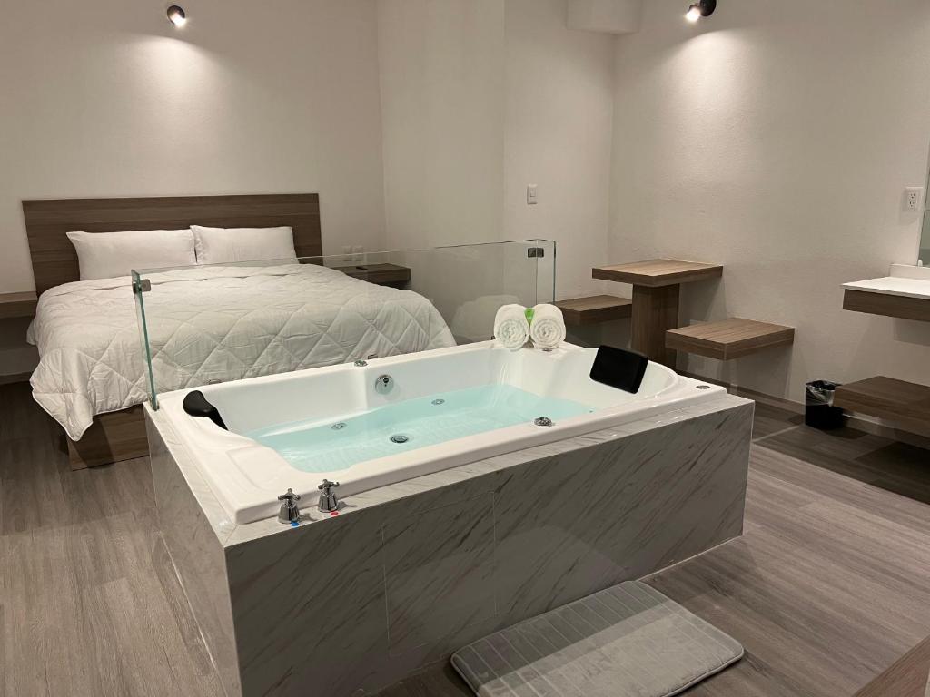 bañera en un dormitorio con cama en Hotel Blanco Pachuca en Pachuca de Soto