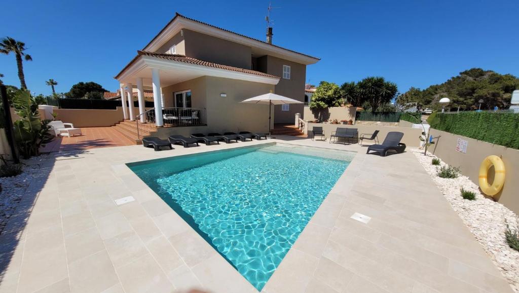 a swimming pool in front of a house at Villa Victoria Paradise in Cala en Blanes