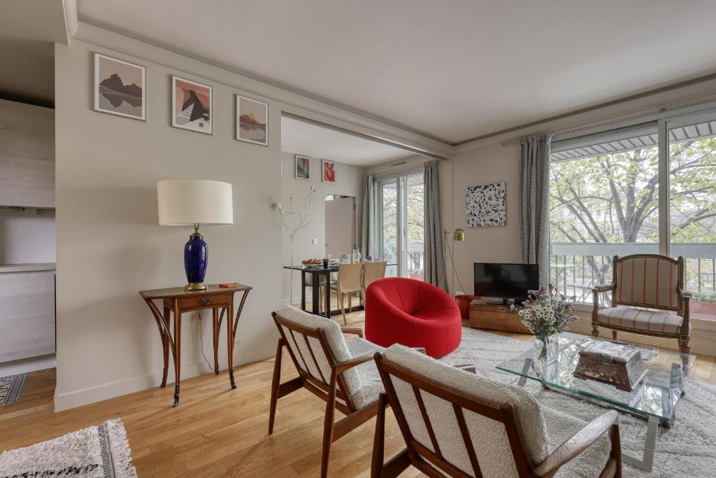 un salon avec une chaise rouge et une table dans l'établissement Luminous & Modern Flat with Balcony Paris-Bastille, à Paris