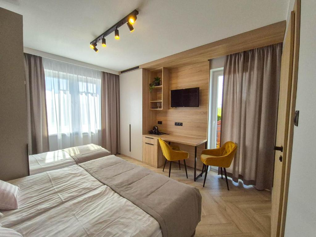 a hotel room with a bed and a desk with chairs at Tramontana Family & Wellness in Darłówko