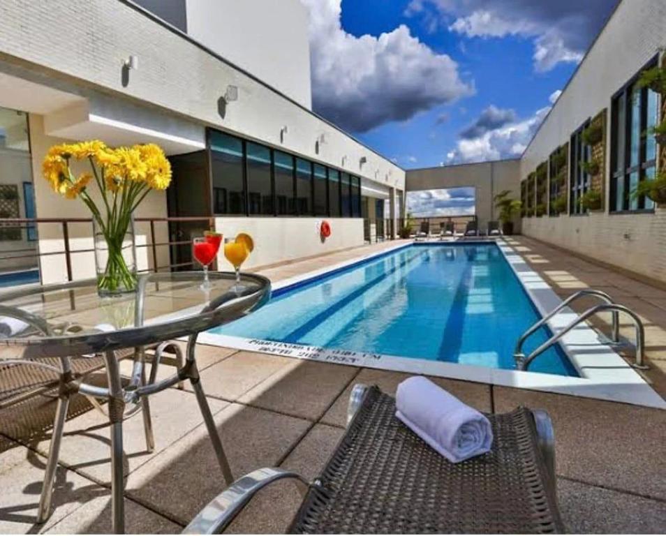 a swimming pool with a glass table and chairs next to a building at Apartamento no Comfot hotel in Brasilia