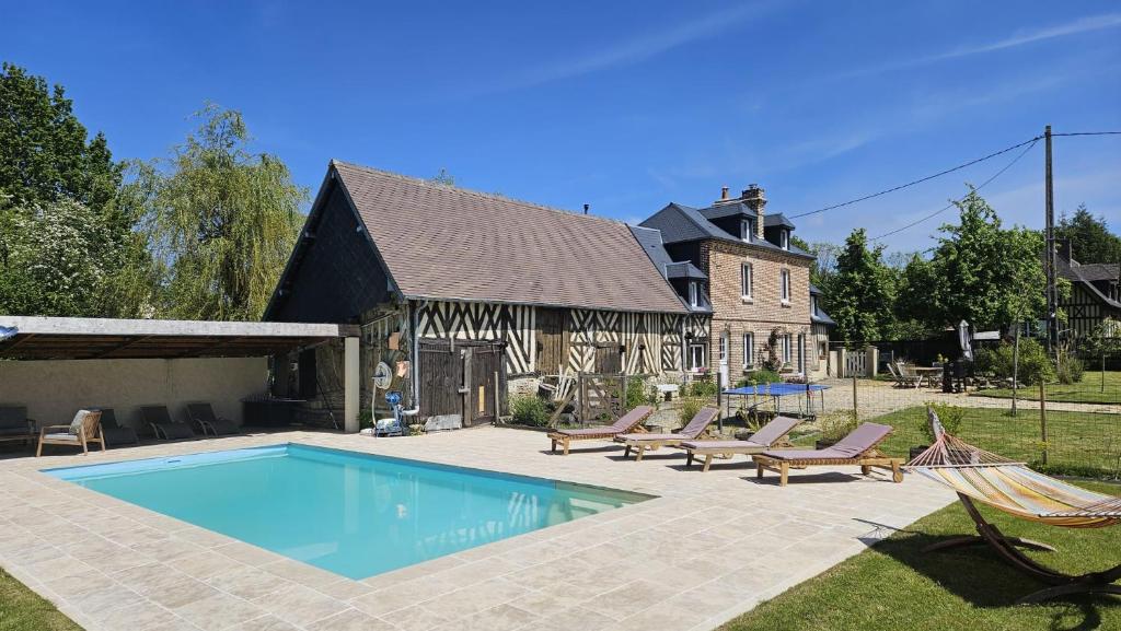 une piscine avec des chaises longues et une maison dans l'établissement Maison de charme - 12 mn de la plage - Piscine chauffée - 8 personnes, à Danestal