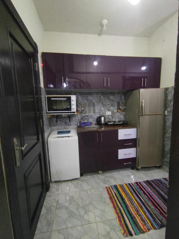 BTM RENTAL CHALETS PORTO MATROUH FAMiLY ONLY في مرسى مطروح: مطبخ مع دواليب ارجوانية وثلاجة