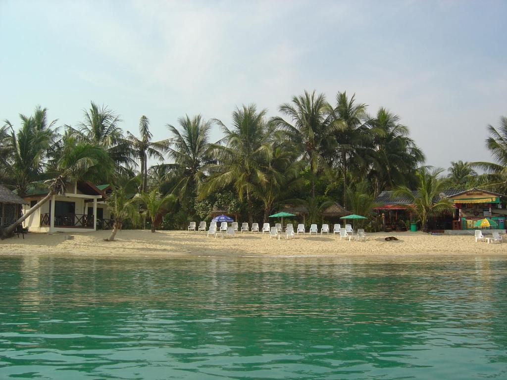 a beach with chairs and umbrellas and palm trees at Moonhut Bungalows in Mae Nam