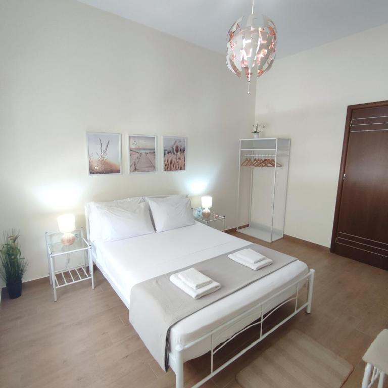 sypialnia z dużym białym łóżkiem i żyrandolem w obiekcie Preveza Mosaic House w Prewezie