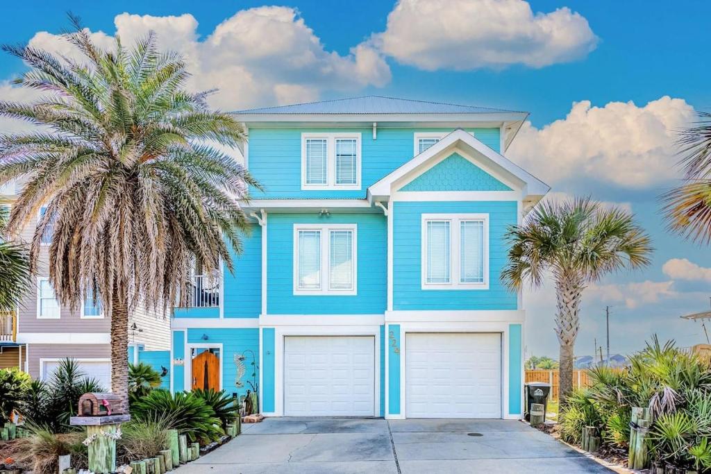 una casa azul con palmeras delante en Crawling Distance Beach House, en Pensacola
