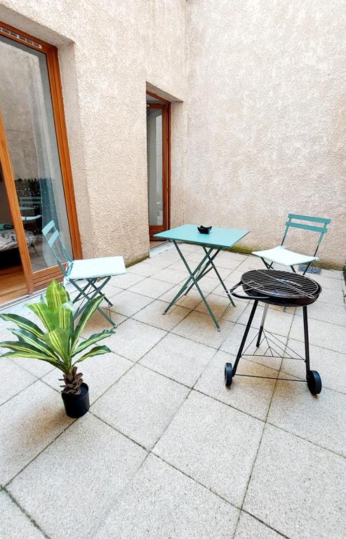une terrasse avec 2 chaises, une table et une plante dans l'établissement Appartement avec terrasse - Orléans - Quai de Loire, à Orléans