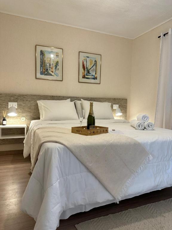 a white bed with a bottle of wine on it at Vinha dos Lagos Hotel in Rancho Queimado