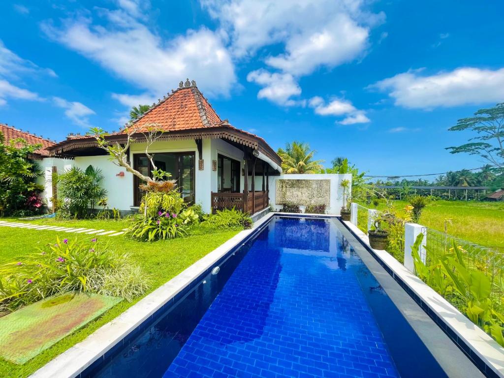 a villa with a swimming pool in front of a house at Umah Teresna in Ubud