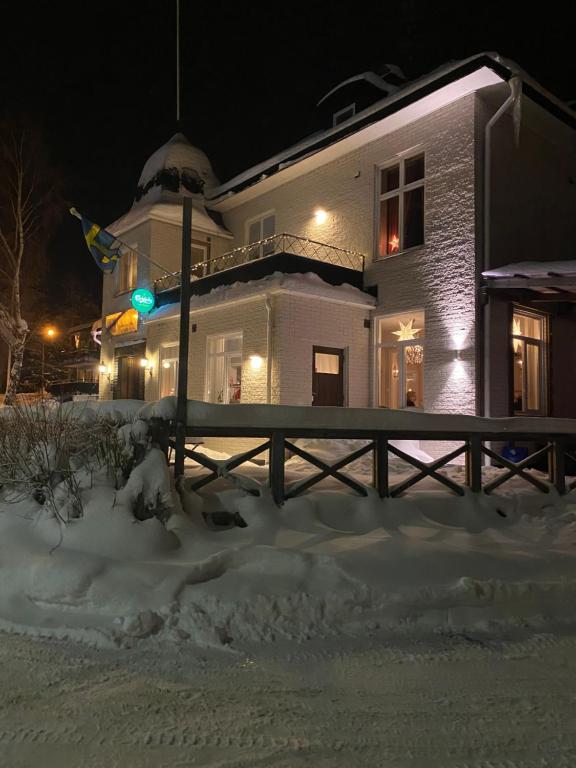 a house with a green traffic light in the snow at Häverödals hotell in Hallstavik