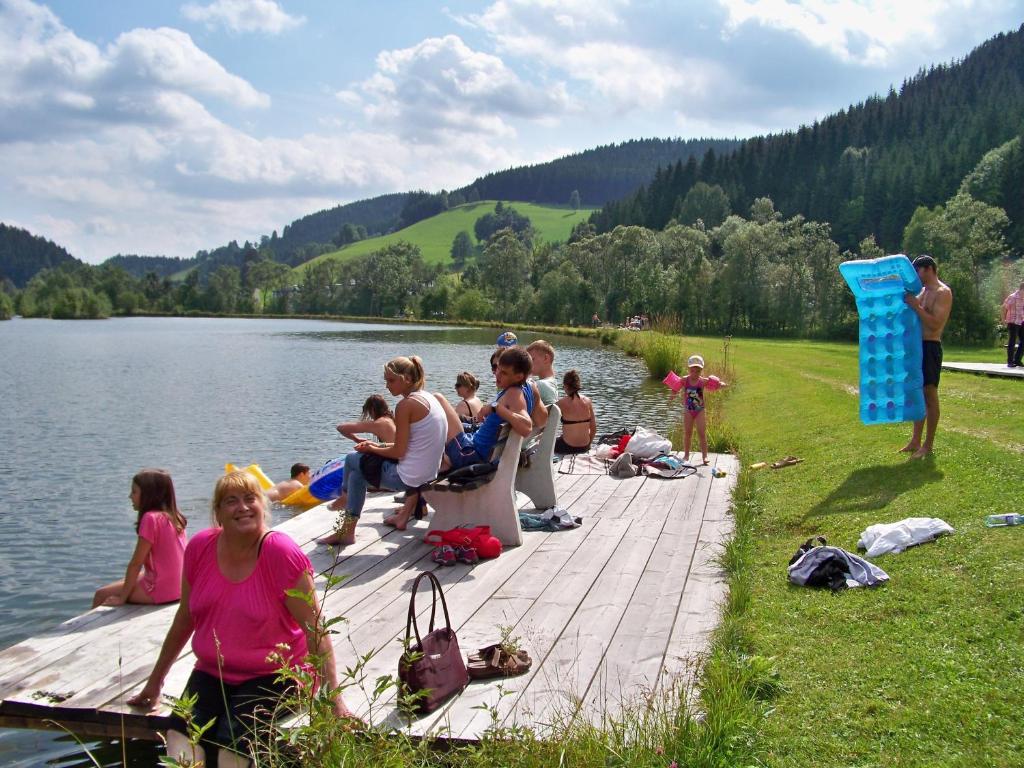 eine Gruppe von Menschen, die auf einem Dock in der Nähe eines Sees sitzen in der Unterkunft Alpenpension Gasthof in Ratten