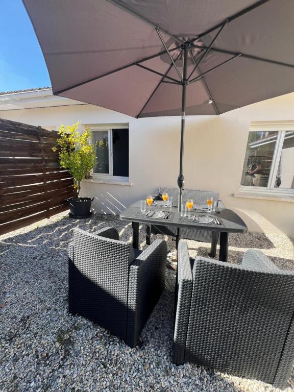 梅里尼亚克La petite Maison Mérignac jardin privé的天井配有桌椅和遮阳伞