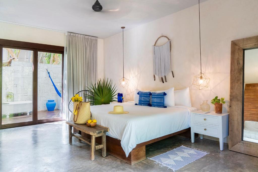 a bedroom with a large white bed with blue pillows at Lula Seaside Boutique Hotel in Tulum