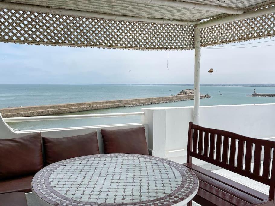 a patio with a table and a view of the ocean at Duplex Statia vue sur Port in El Jadida
