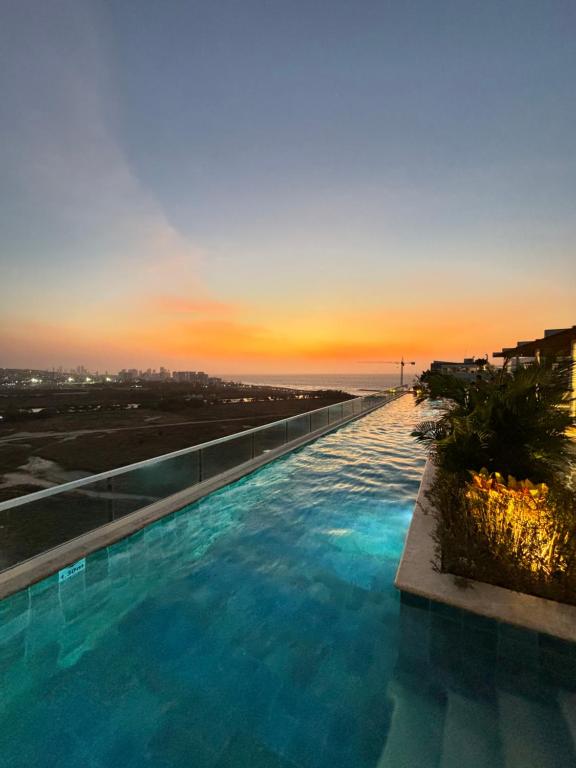 a large swimming pool with a sunset in the background at Dominique By Stay Q in Cartagena de Indias