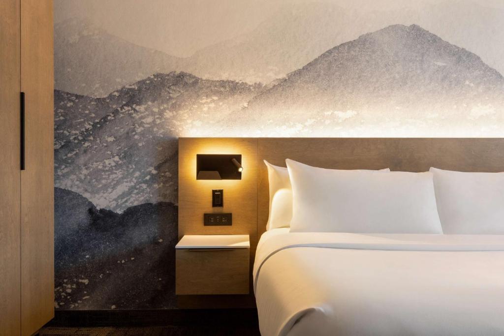Ce lit se trouve dans une chambre d'hôtel ornée d'une fresque murale de montagne. dans l'établissement Hôtel Québec Best Western PLUS Centre-Ville - City Center, à Québec