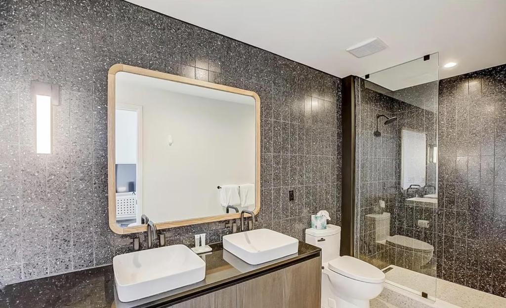 a bathroom with two sinks and a mirror and a toilet at Luxury Oasis on Rainy Street in Austin