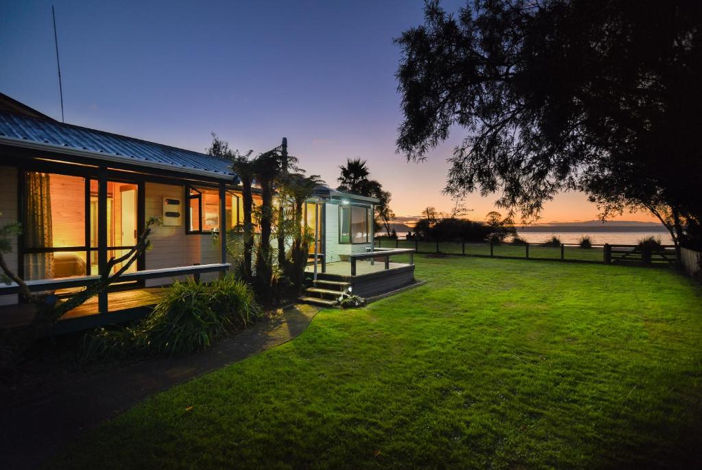 una casa con un patio de césped al lado de un edificio en Cooper's Lakeside Cabin, en Rotorua