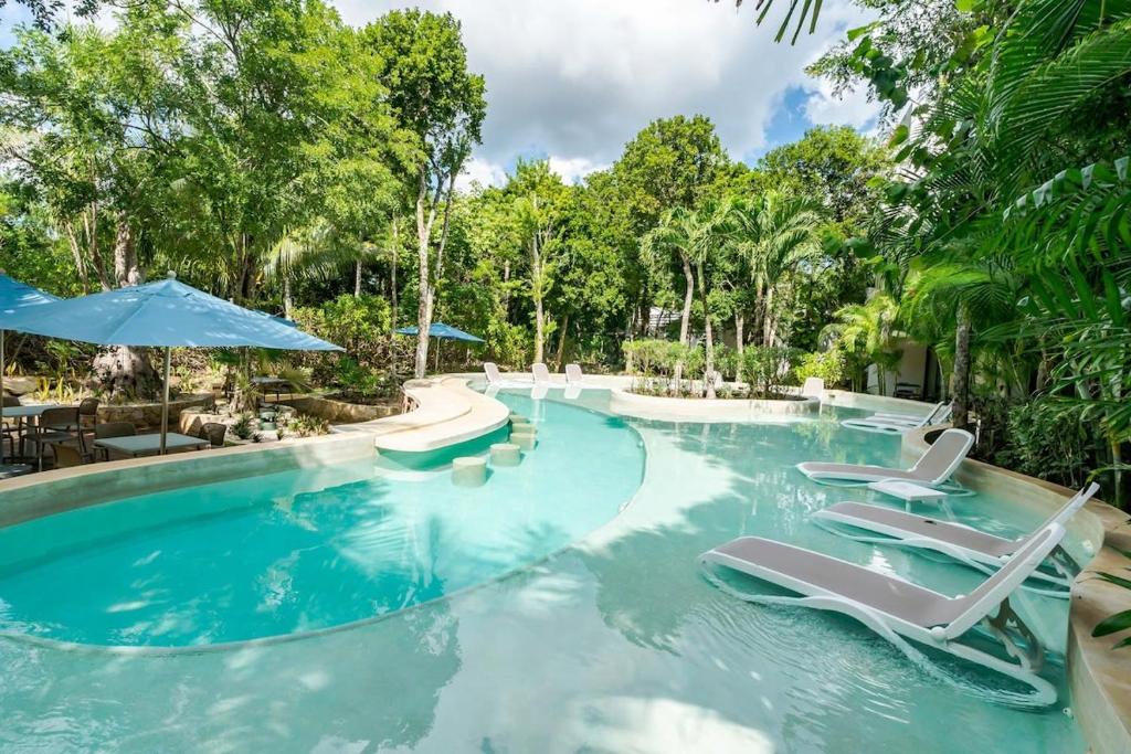 a pool at a resort with chairs and umbrellas at LUXE 1-BR Condo in Bahia Principe - Multiple Pools in Akumal