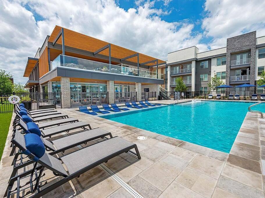 a swimming pool with lounge chairs in front of a building at Ft Worth 1BR Luxury Retreat in Fort Worth