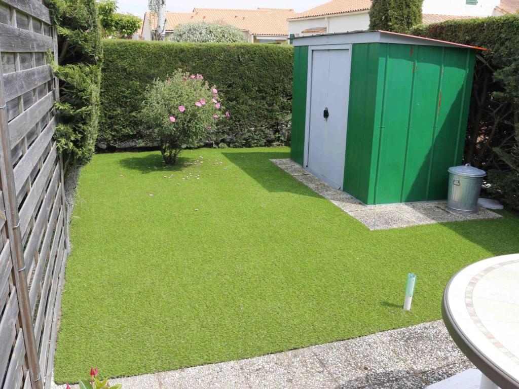 un jardin avec une dépendance verte et blanche dans l'établissement Maison aux Mathes : Piscine, Tennis, Proche Plage et Commerces - FR-1-705-50, aux Mathes