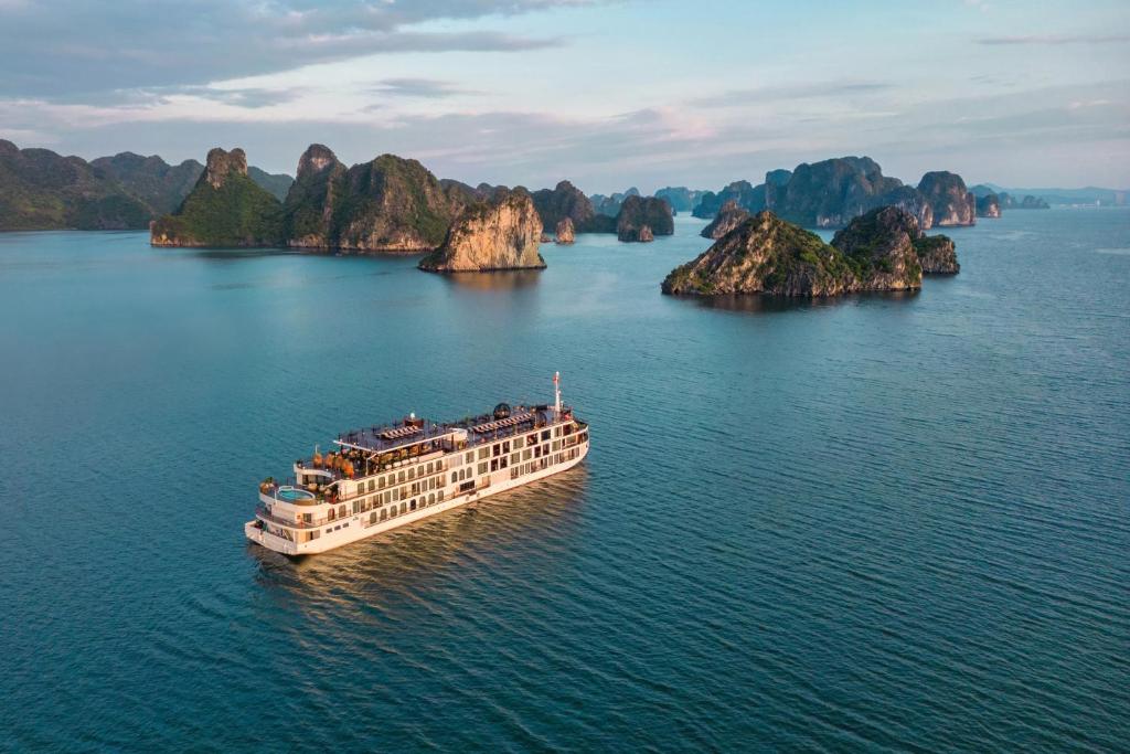 Indochine Premium Halong Bay Powered by Aston في ها لونغ: سفينة الرحلات البحرية في الماء بالقرب من بعض الجزر