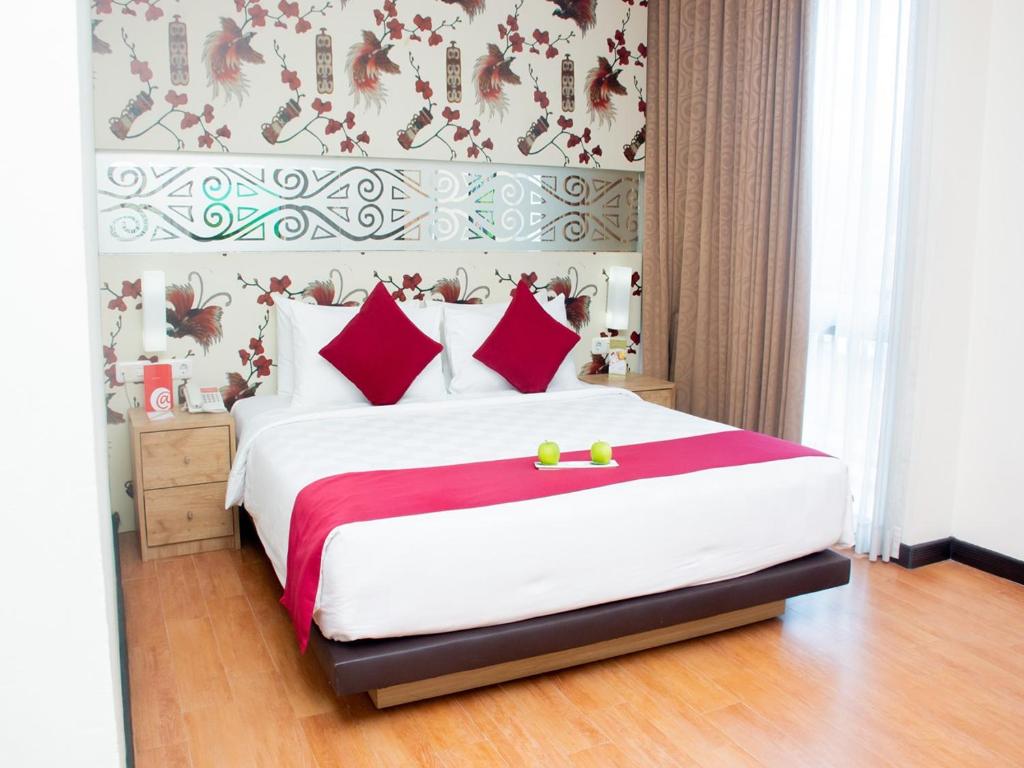 ein Schlafzimmer mit einem großen weißen Bett mit roten Kissen in der Unterkunft @Hom Premiere by Horison Abepura in Abepura