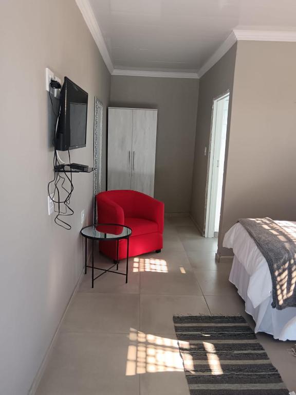 a bedroom with a red chair and a bed at The Space Guesthouse Mondlo in Mondlo