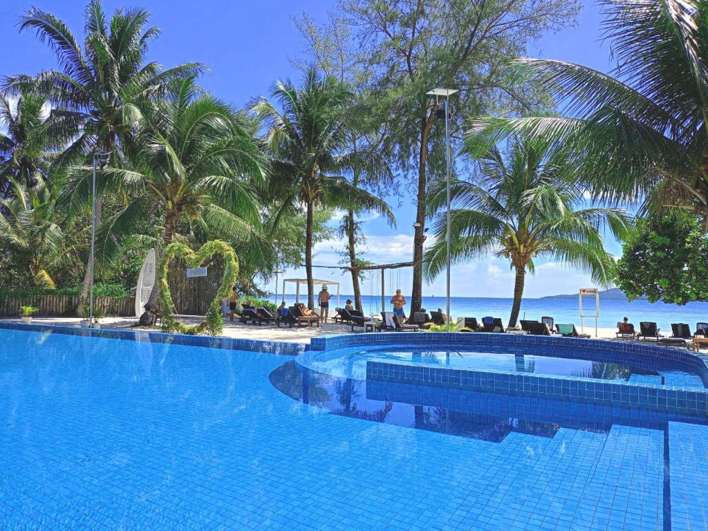 een groot zwembad met palmbomen en de oceaan bij SCARLET SAILS BUNGALOW in Koh Rong Island