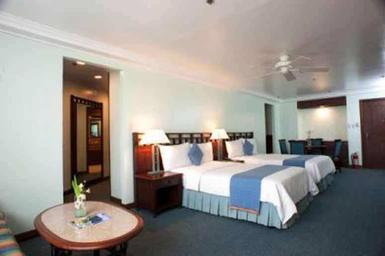 una habitación de hotel con una cama grande y una mesa en A paradise nestled in the City of Pines, Camp John Hay Baguio City, en Baguio