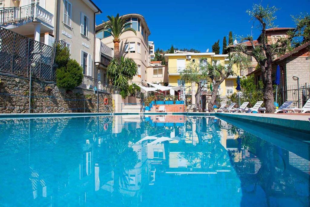 a swimming pool with blue water in front of buildings at Hotel Villa Igea in Diano Marina
