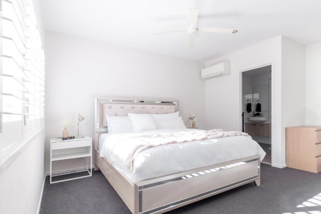 Beautiful Modern 3 Bedroom Family Suite Sleeps 6 في بريزبين: غرفة نوم بيضاء مع سرير وحمام