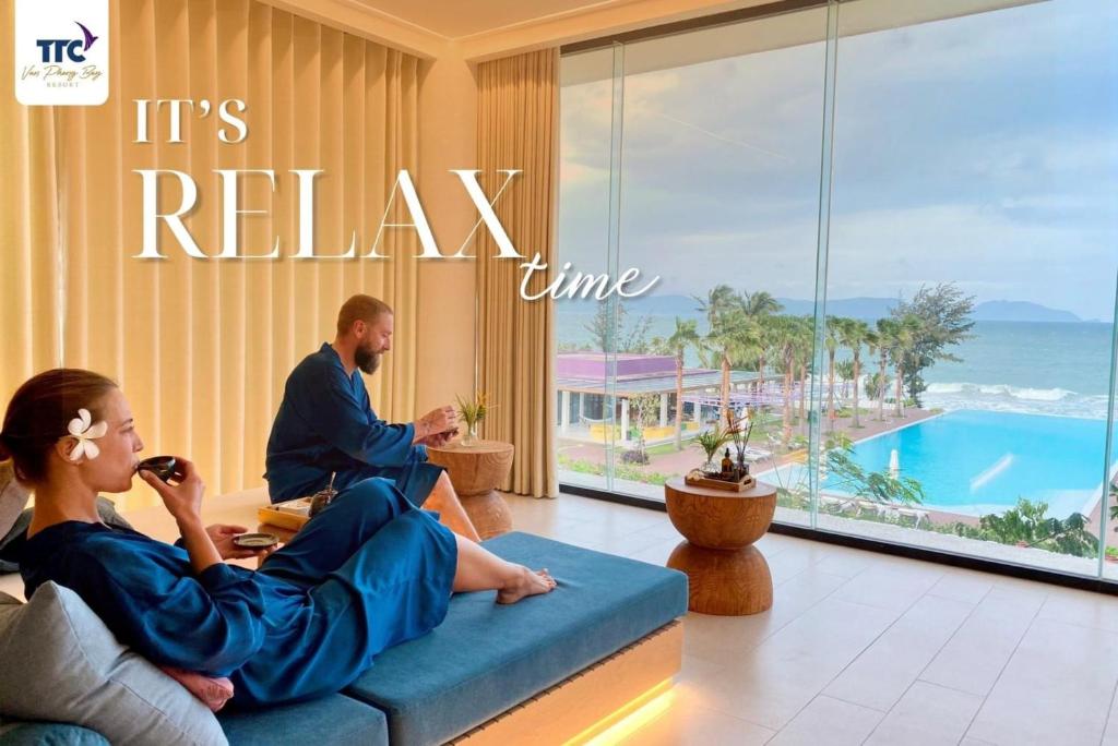 a man and woman sitting on a couch in a hotel room at TTC Van Phong Bay Resort - Himalaya Sauna & Steam Retreat Included in Ninh Hòa
