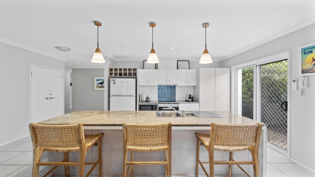 a kitchen with a large island with four chairs at Aqua Links 70 The Drive Yamba in Yamba