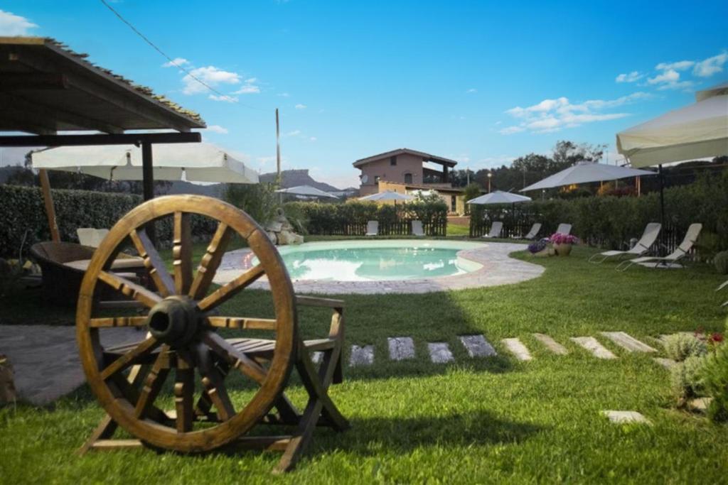 una rueda de madera sentada en el césped junto a una piscina en La Pinnetta With Pool - Happy Rentals, en Codrongianos