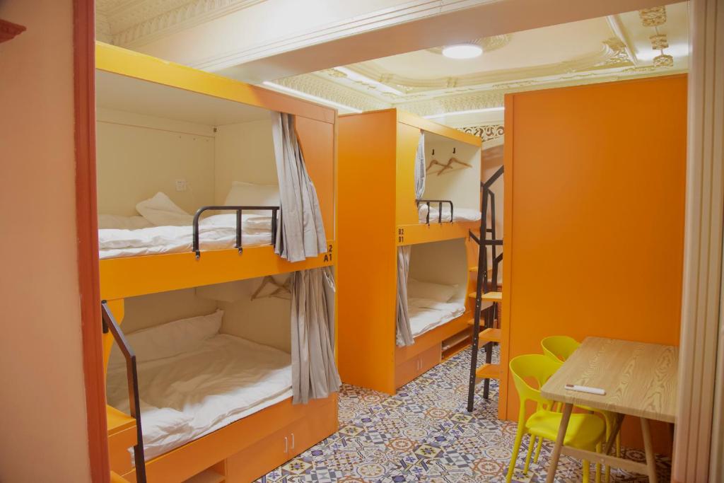 a room with orange bunk beds and a table at 浪子小栈Kashgar Ancient City in Kashgar