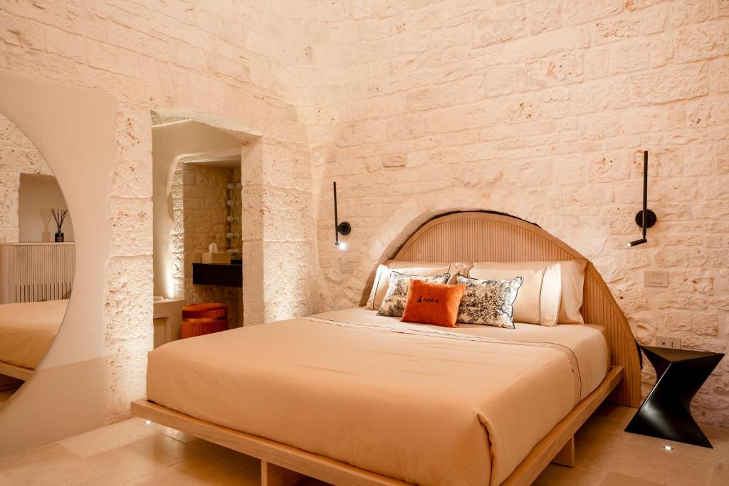 - une chambre avec un grand lit dans un mur en pierre dans l'établissement Naiira Luxury Trullo, à Alberobello