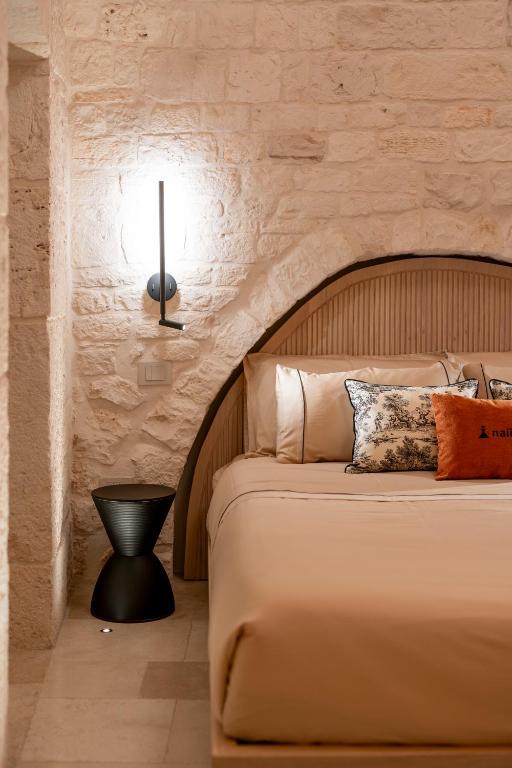 a bedroom with a large bed with a stone wall at Naiira Luxury Trullo - jacuzzi and patio in Alberobello