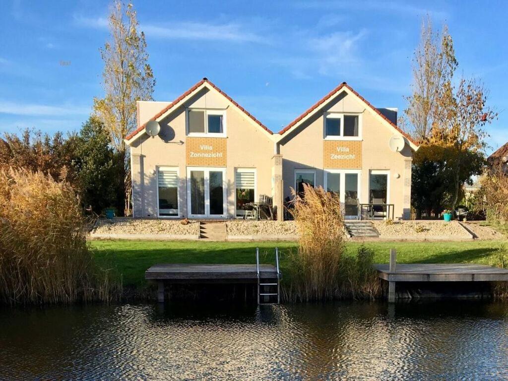 a house with a lake in front of it at Villa Sunlight Comfortable Vacation Home in Makkum