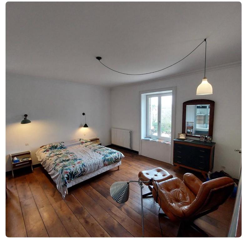 1 dormitorio con cama, espejo y silla en Le Clos Saint Roch, en Saint-Amand-Jartoudeix