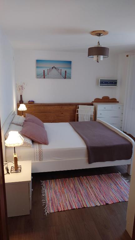 Un dormitorio con una cama grande y una mesa con una lámpara. en da Dorian en Punat