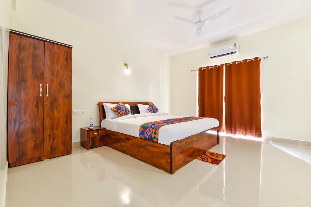 a bedroom with a bed and a wooden cabinet at FabHotel Sterling Garden in Old Goa