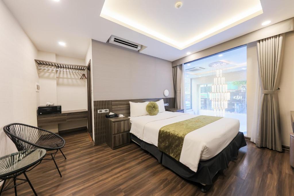 ハノイにある3T Hotel Hanoiのベッドと大きな窓が備わるホテルルームです。