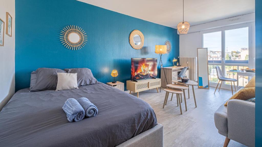 une chambre avec un lit et un mur bleu dans l'établissement Bleu Paon - Welc'Home, à Limoges