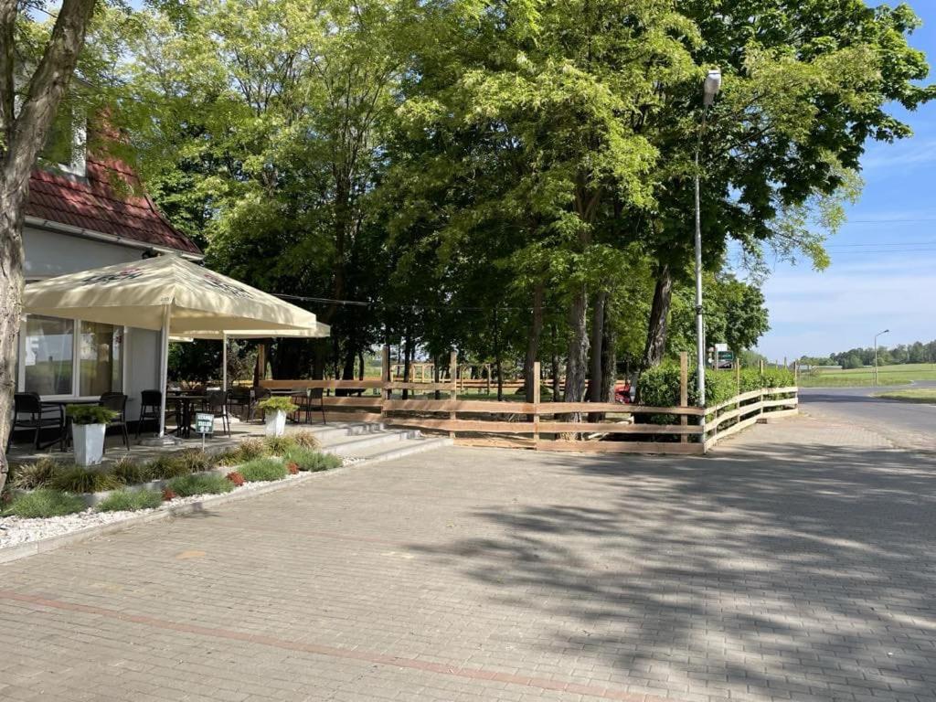 Myszęcin的住宿－Gościniec，路边有栅栏和雨伞的建筑